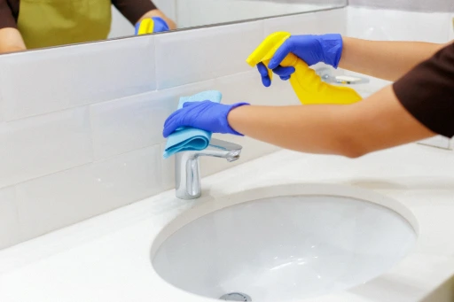 Persona con guantes limpiando lavabo del baño